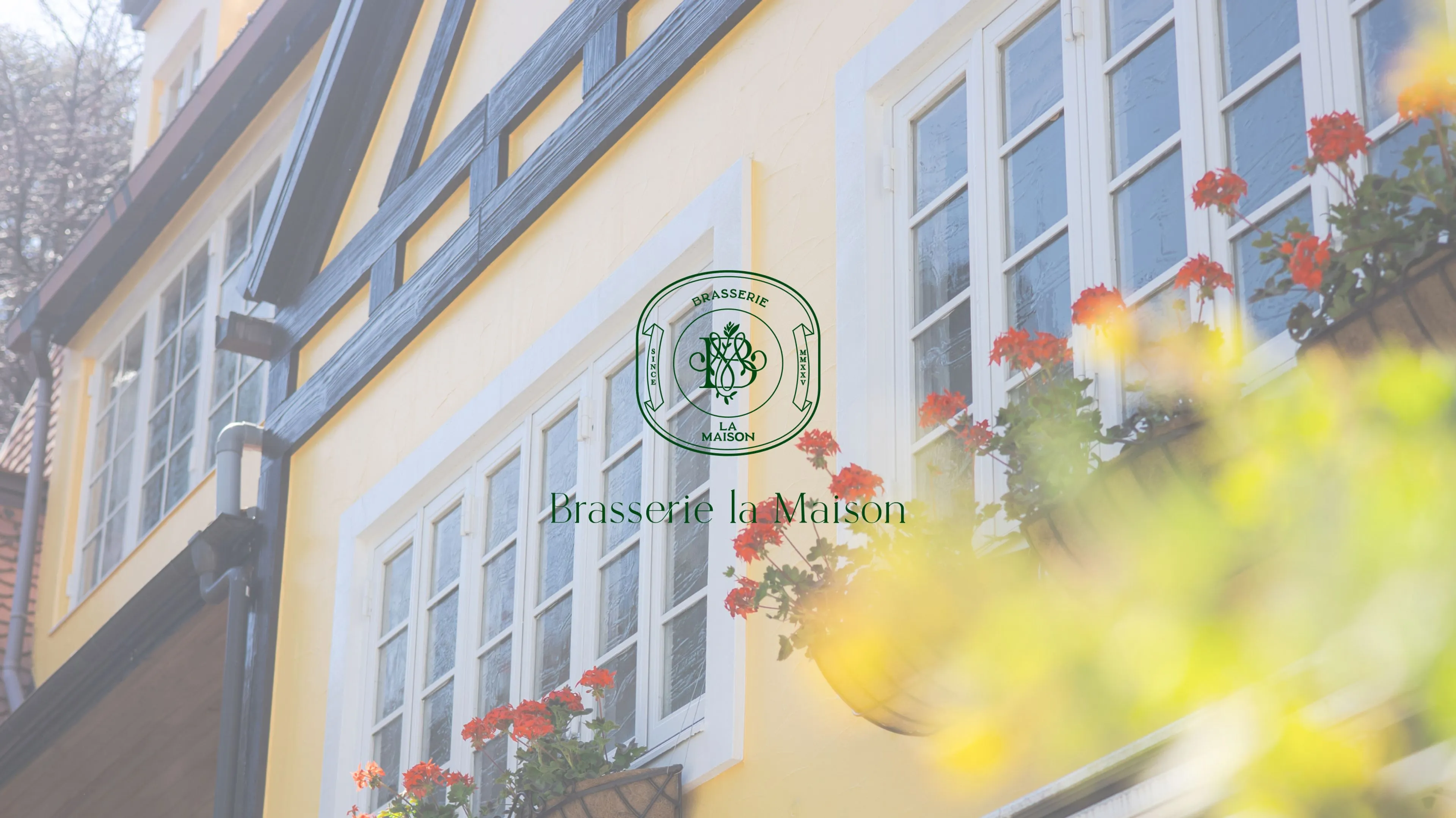レストラン ブラッスリー・ラ・メゾンの外観に緑色のロゴと店名 Brasserie la Maison
